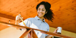 woman painting exterior fence railing